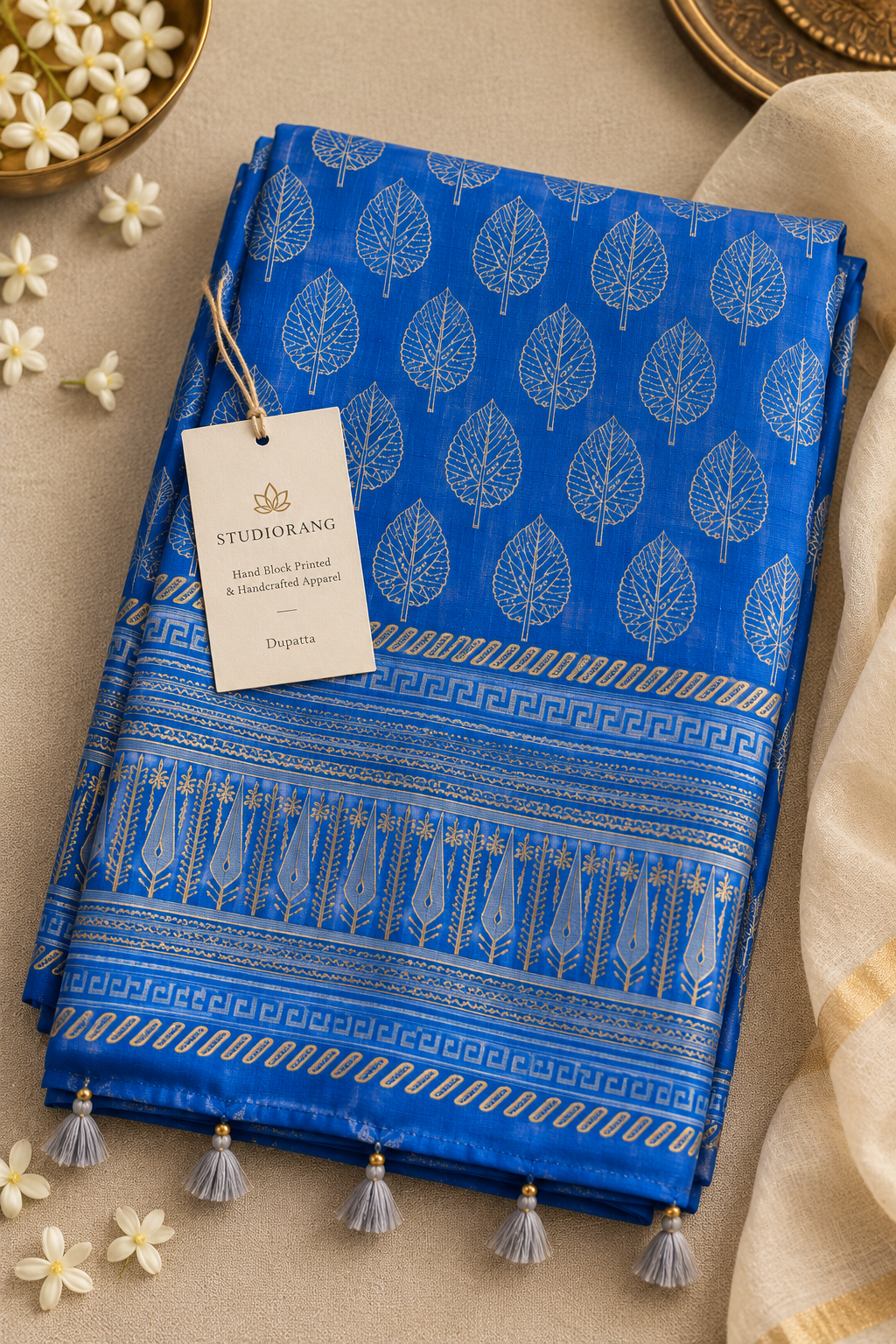 Folded blue Chanderi dupatta showing leaf motifs, printed border, tassels, and Studio Rang tag