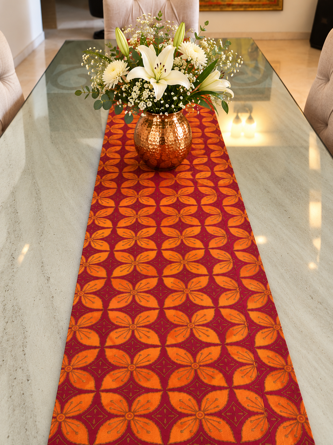 Maroon and orange floral dupion silk table runner styled on a glass dining table with a flower vase