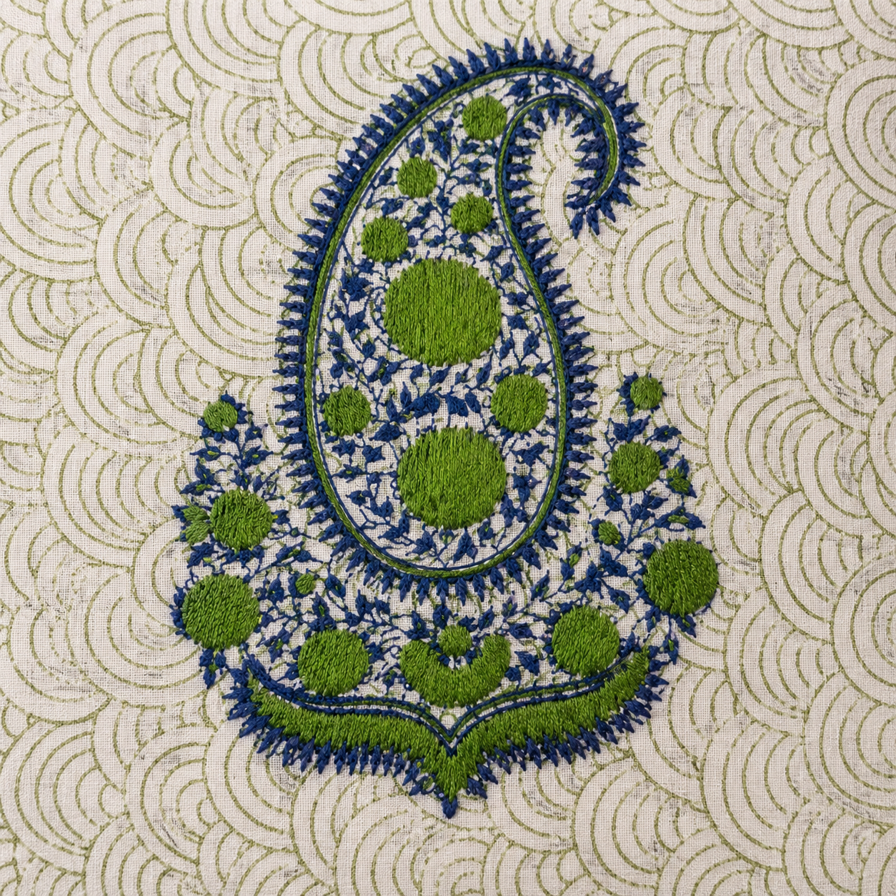 Close up of green navy hand embroidered paisley on scallop block printed cotton cushion cover