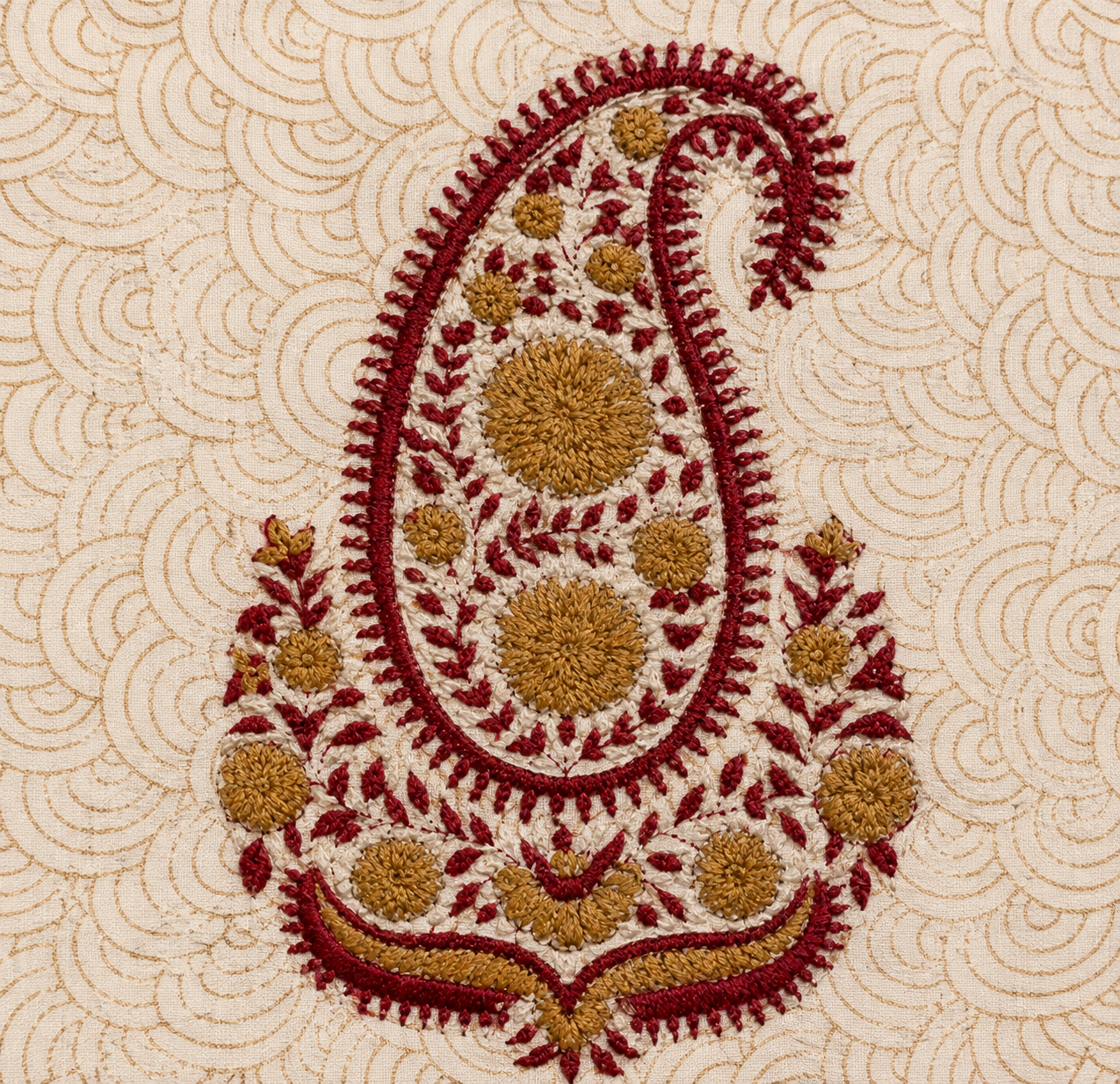Close up of maroon gold hand embroidered paisley on scallop block printed cotton cushion cover
