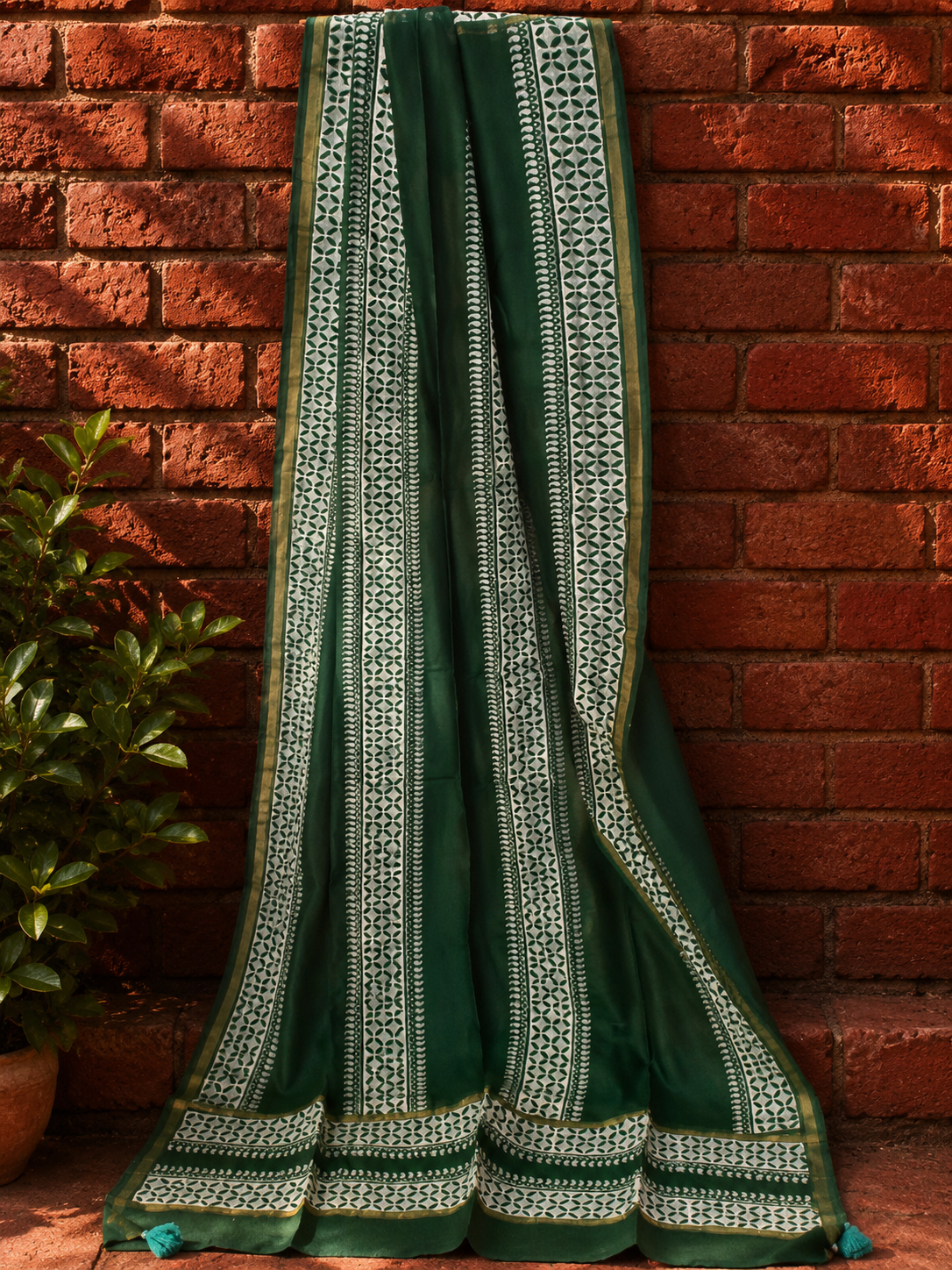 Forest green Chanderi dupatta with intricate hand block printed border, draped against brick wall